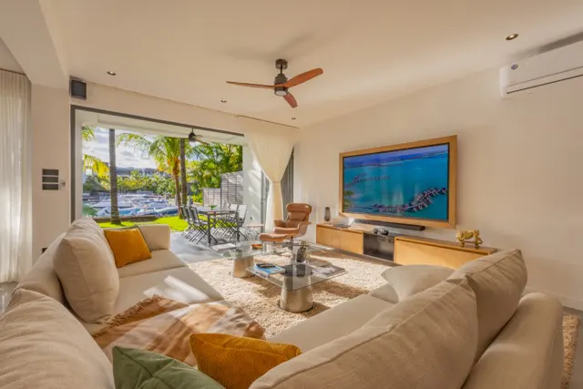 Living room with a large white sofa, TV, and open patio with a view of a marina.