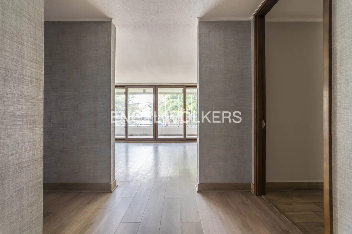 An interior view of a room with hardwood floors, gray textured walls, and a doorway to a balcony with glass doors.