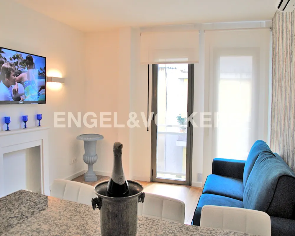 Living room with a blue sofa, TV, fireplace, and champagne in an ice bucket on a granite table. Balcony in the background.