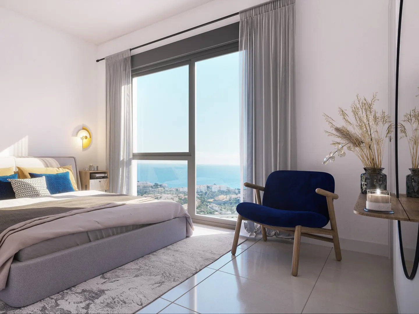 A bright bedroom with a large window overlooking the ocean, a bed with blue pillows, and a blue chair.