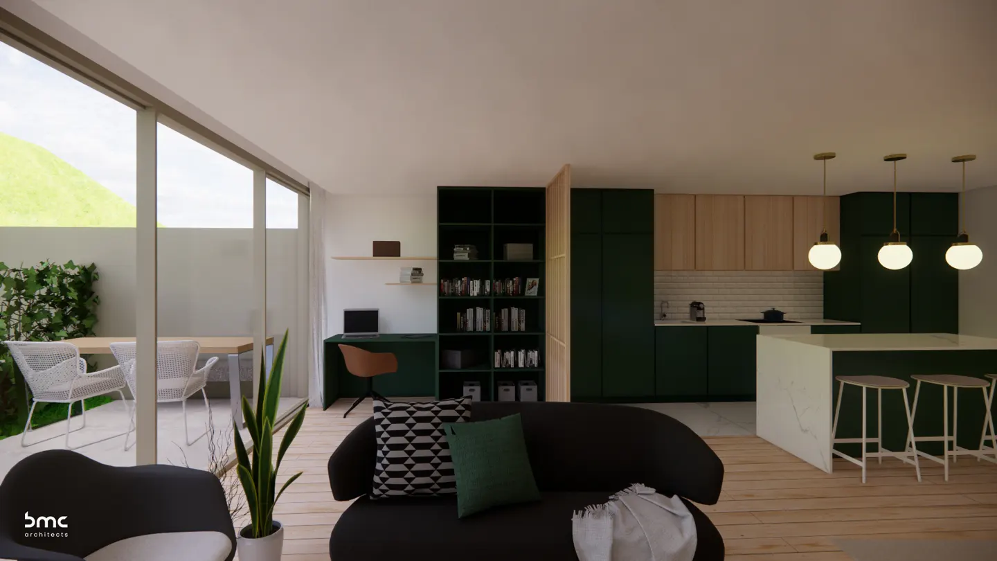 A modern living space with a black sofa, green cabinets, and a kitchen island with stools. Natural light streams through large windows.