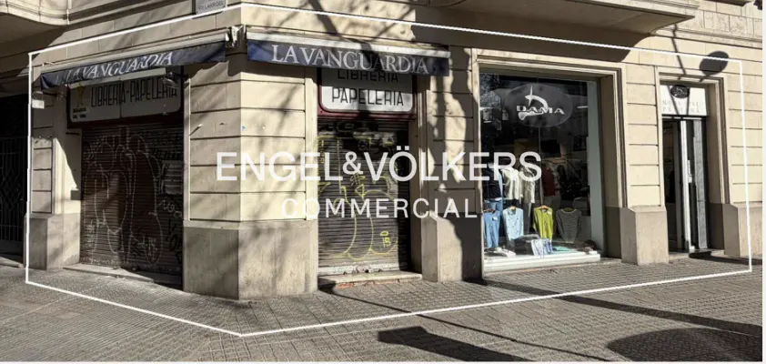 Exterior view of a commercial building with "Engel & Völkers Commercial" displayed on the window. One storefront is closed with a metal shutter, the other is a clothing store.