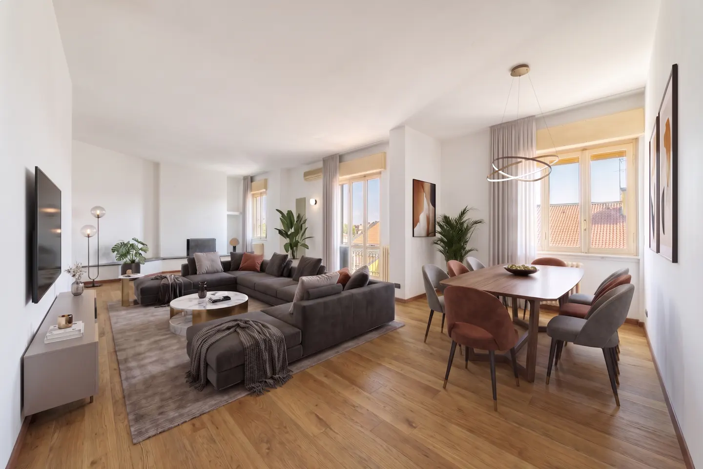 Bright, open-concept living and dining area with wood floors. A gray sectional sofa faces a TV. A wood table with six chairs sits near a window.