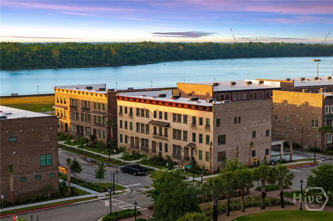 Aerial view of brick townhouses near a river under a blue and pink sky at sunset.