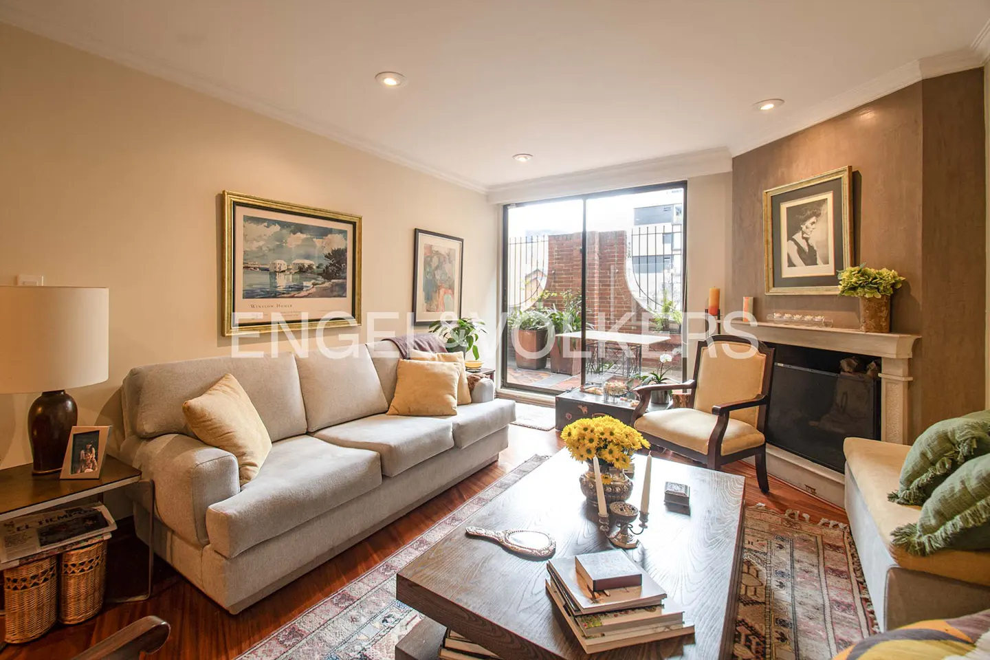 Cozy living room with a beige sofa, wooden coffee table, fireplace, and sliding glass doors leading to a balcony.