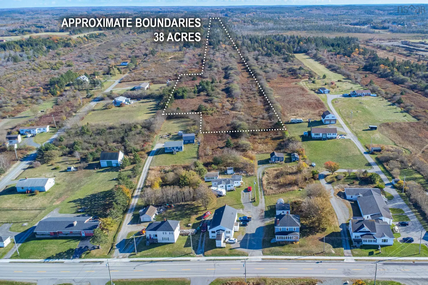 Aerial view of a 38-acre property with dotted white lines marking its boundaries, surrounded by trees and houses.