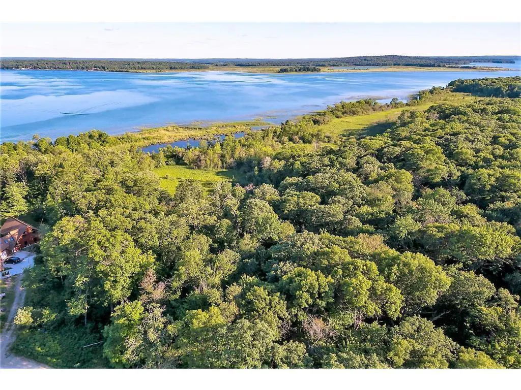 Aerial view of a wooded property with a lake in the background, showcasing real estate potential.