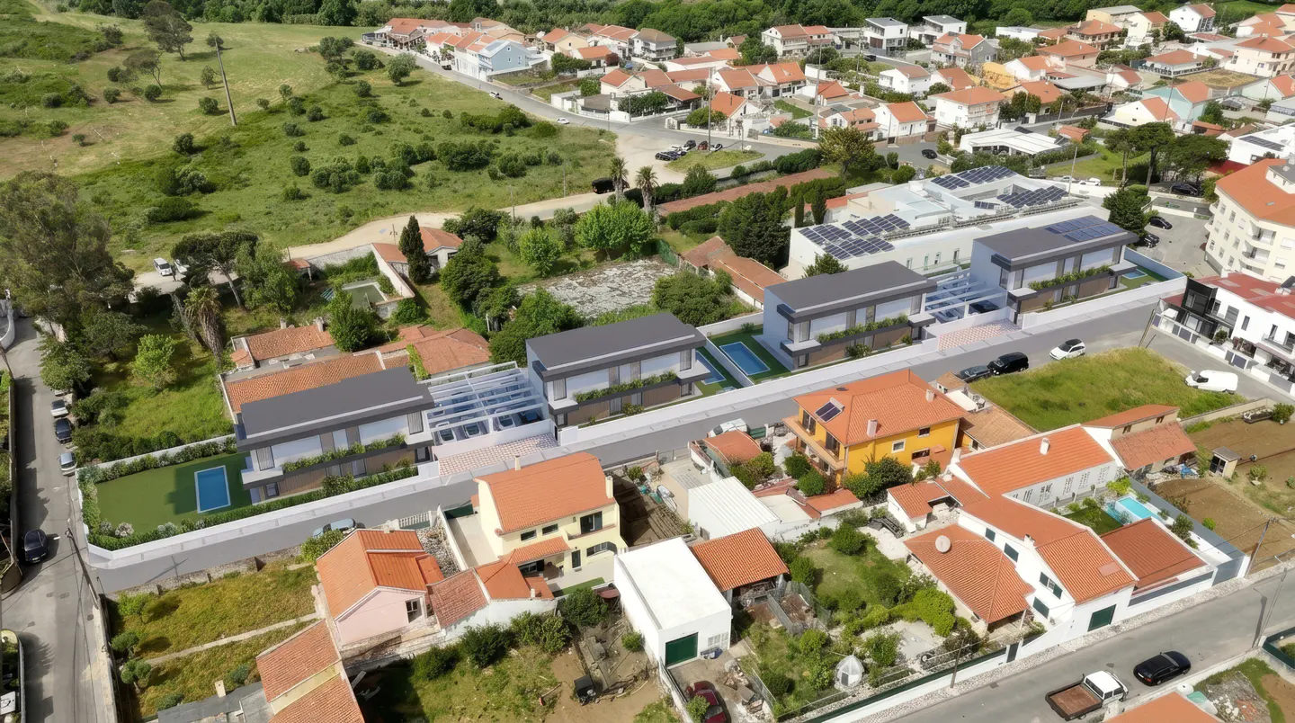 Aerial view of modern gray-roofed houses with pools, surrounded by older homes with orange roofs in a residential area.