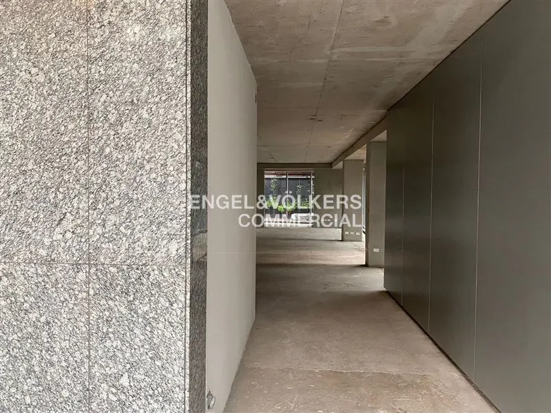 Interior view of a commercial space with gray walls, concrete floors and ceilings, and a granite pillar. "Engel & Volkers Commercial" logo is visible.