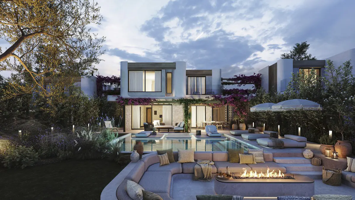 Luxury home exterior at dusk with a pool, fire pit, and lounge seating. Bougainvillea climbs the white walls.