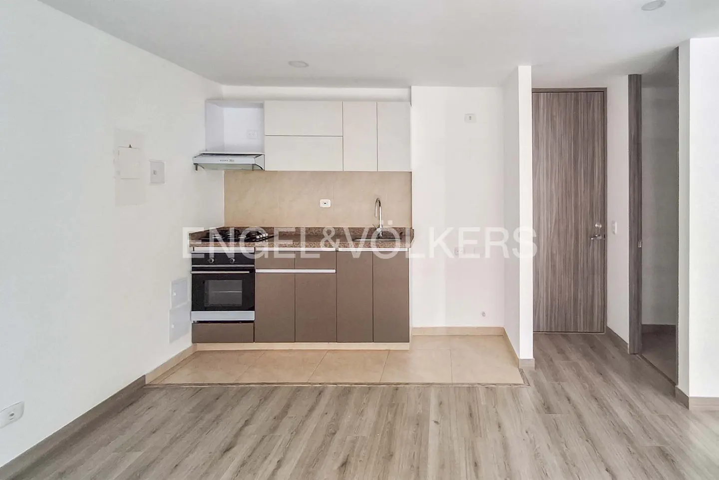 Modern kitchen with white upper cabinets, brown lower cabinets, stainless steel oven, and light wood-look flooring.