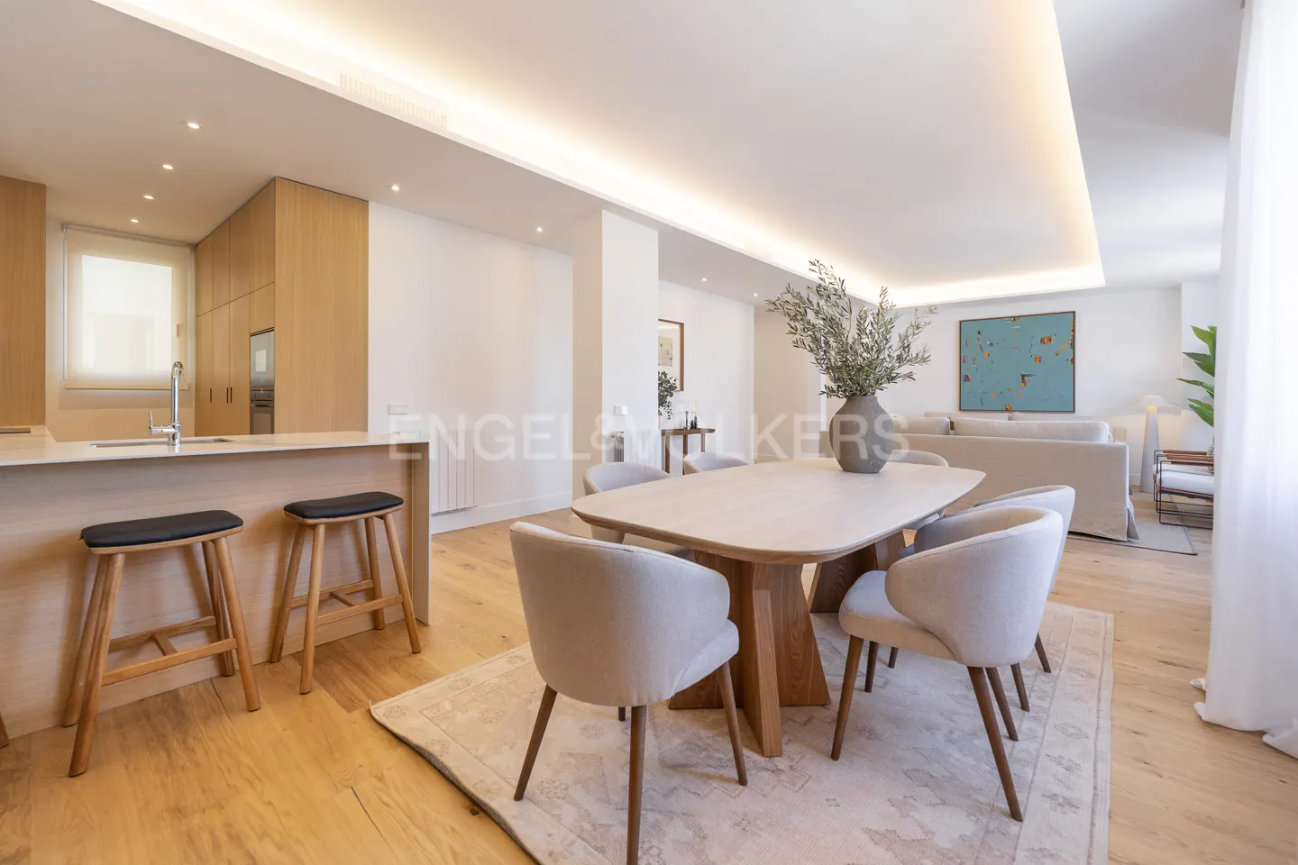 Open-concept living space with a kitchen island, dining table with six chairs, and a living room with a sofa.
