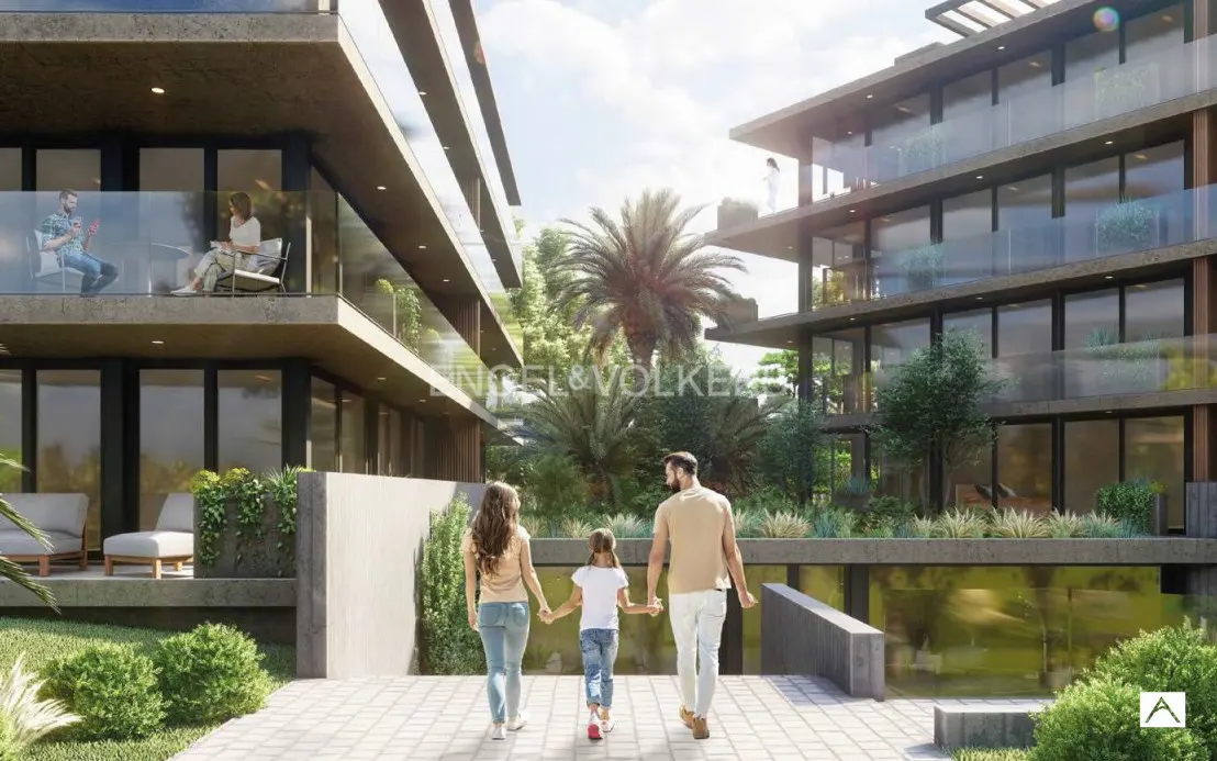 A family walks toward modern apartment buildings with balconies, lush greenery, and palm trees on a sunny day.