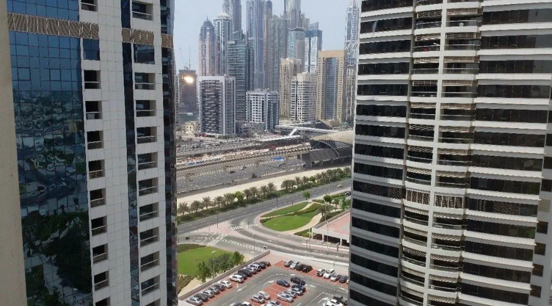 View from a high-rise building, showing a cityscape with skyscrapers, roads, and a parking lot.