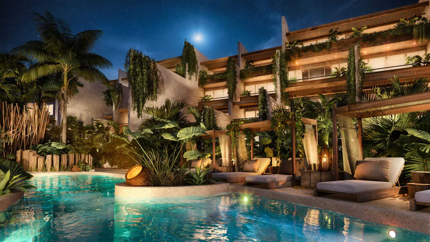 Night view of a luxury resort with a pool, lounge chairs, and lush greenery. The building has balconies with plants.