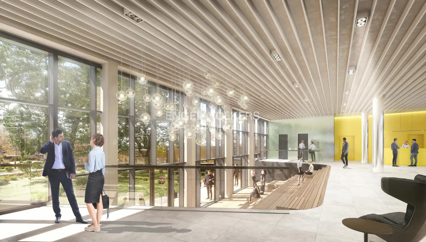 Bright, modern lobby with floor-to-ceiling windows overlooking a garden. People are walking, talking, and sitting. Yellow accent wall.