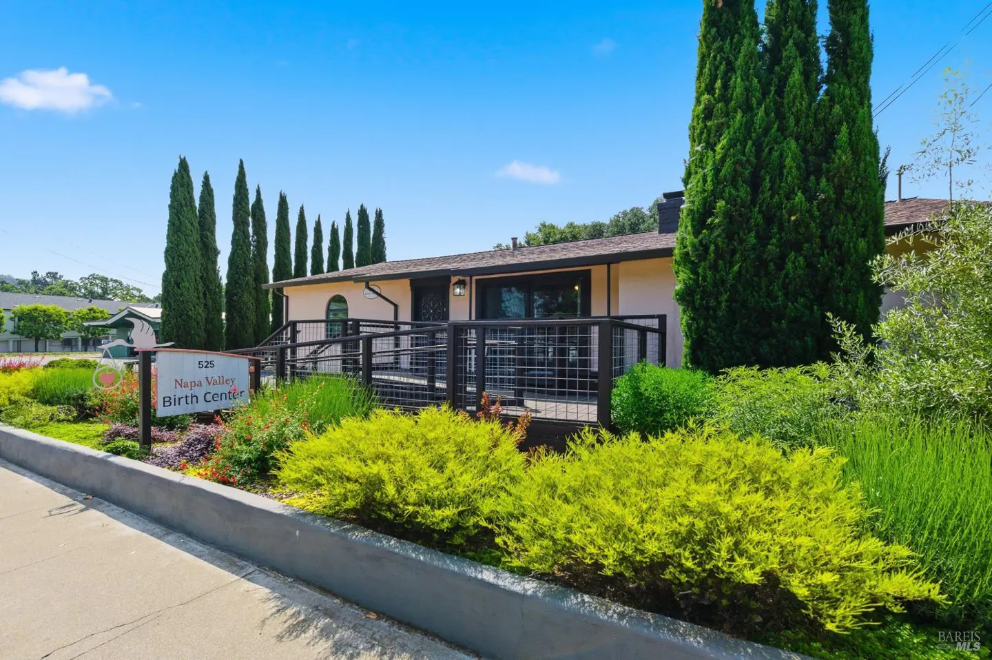Exterior view of Napa Valley Birth Center, a one-story building with a ramp, surrounded by greenery and tall trees.
