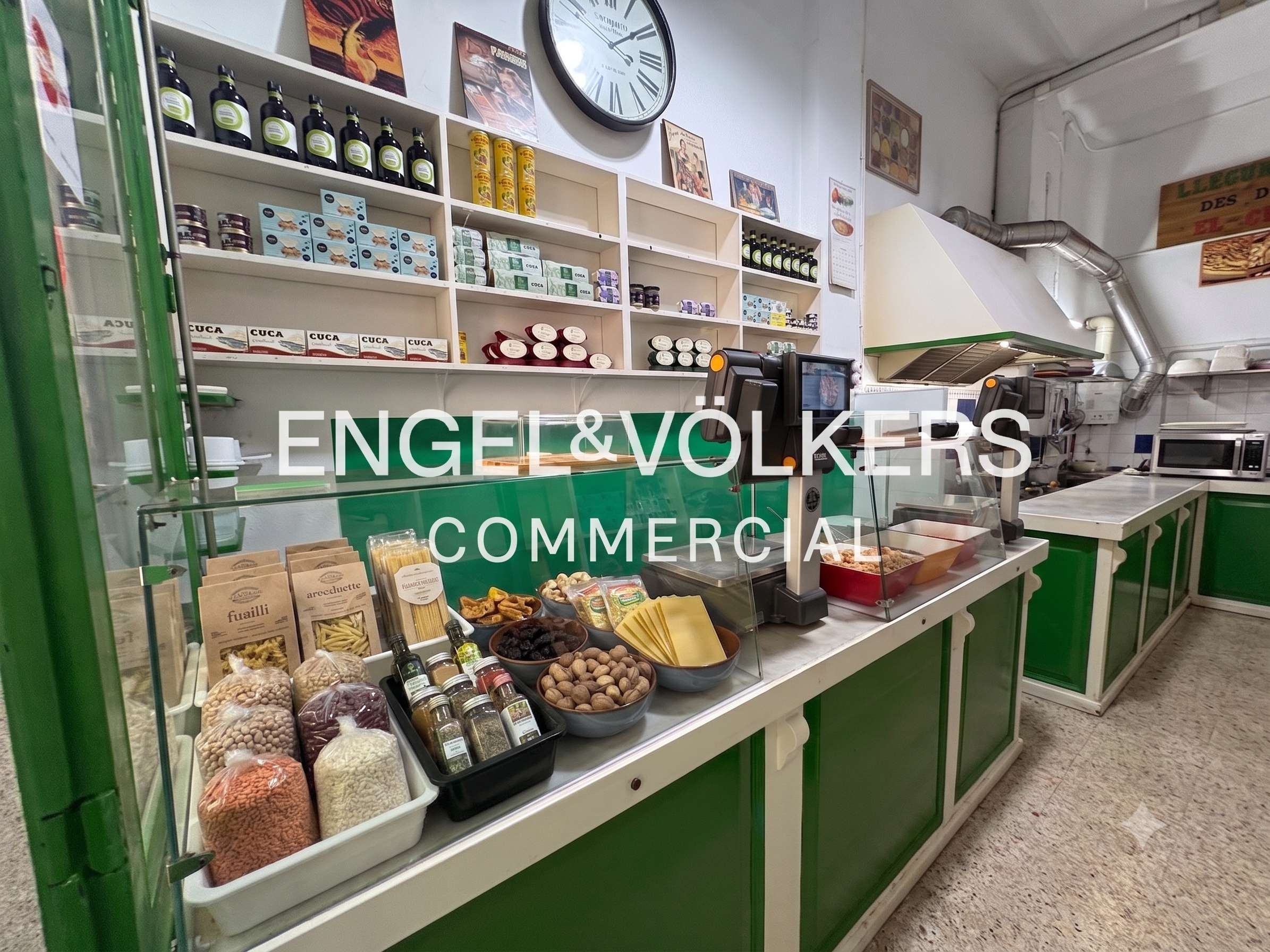 Interior of a deli with green counters, shelves stocked with food products, a large wall clock, and a glass display case.