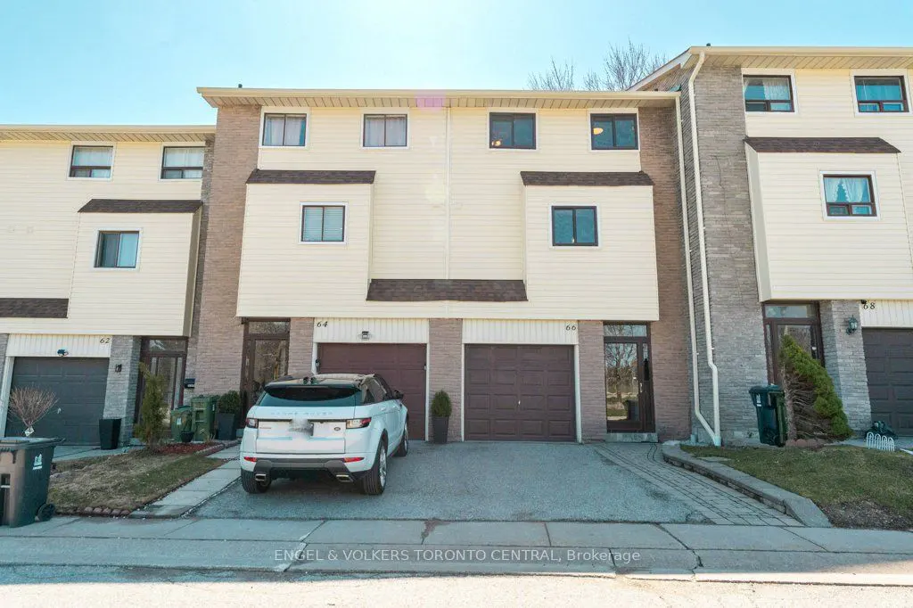 Three-story townhouses with beige siding and brick accents, brown garage doors, and a white Range Rover parked in front.
