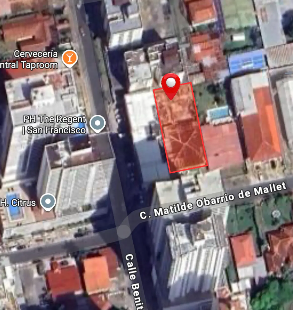Aerial view of a property outlined in red with a red pin, surrounded by buildings and streets.