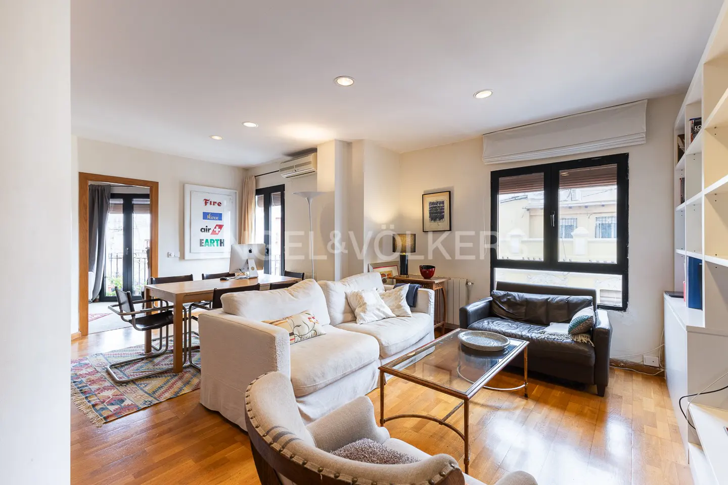 Bright living room with hardwood floors, a white sectional sofa, a dark leather loveseat, and a dining area.