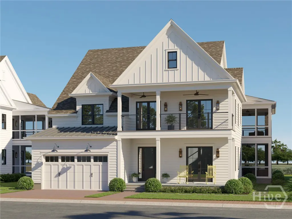 Two-story white farmhouse with a front porch, balcony, attached garage, and yellow chairs under a clear blue sky.