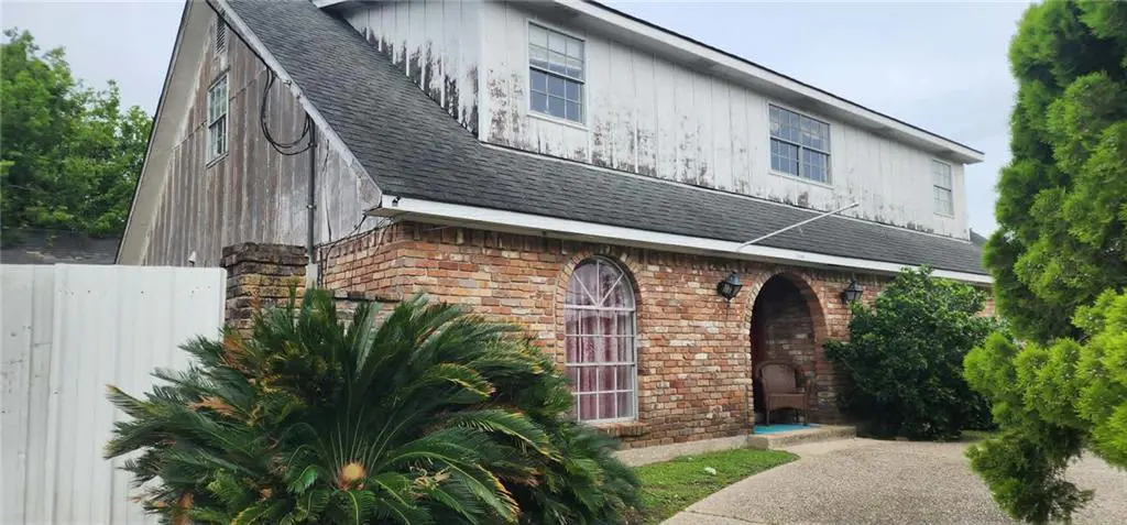 Exterior of a two-story house with brick and white siding, arched windows, and a walkway.