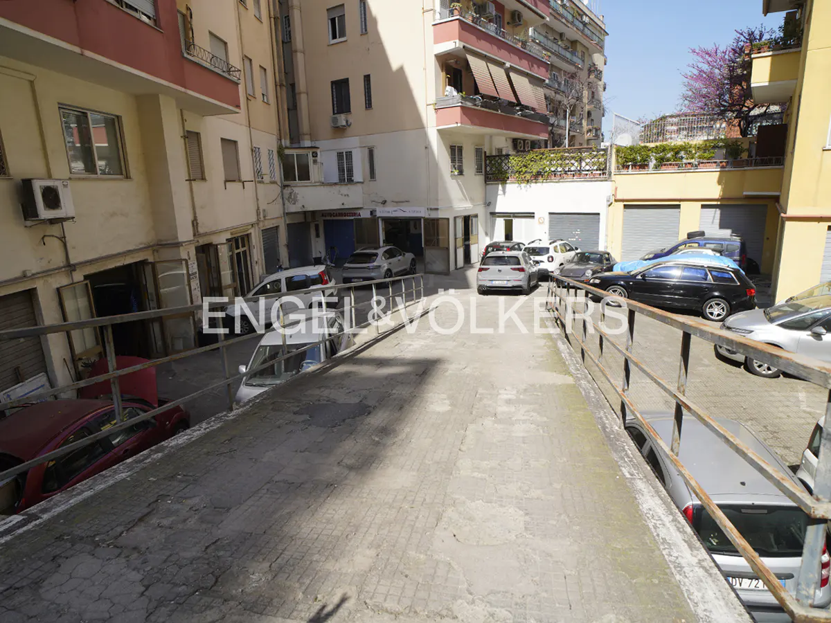 Exterior view of a parking area with multiple cars parked in front of buildings.