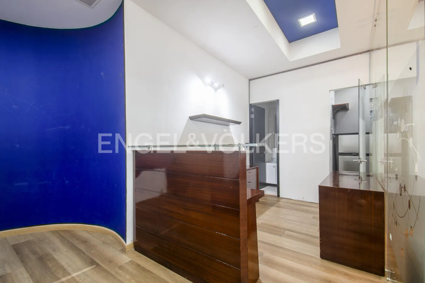 Interior view of a real estate office with a dark wood reception desk and blue accent wall.