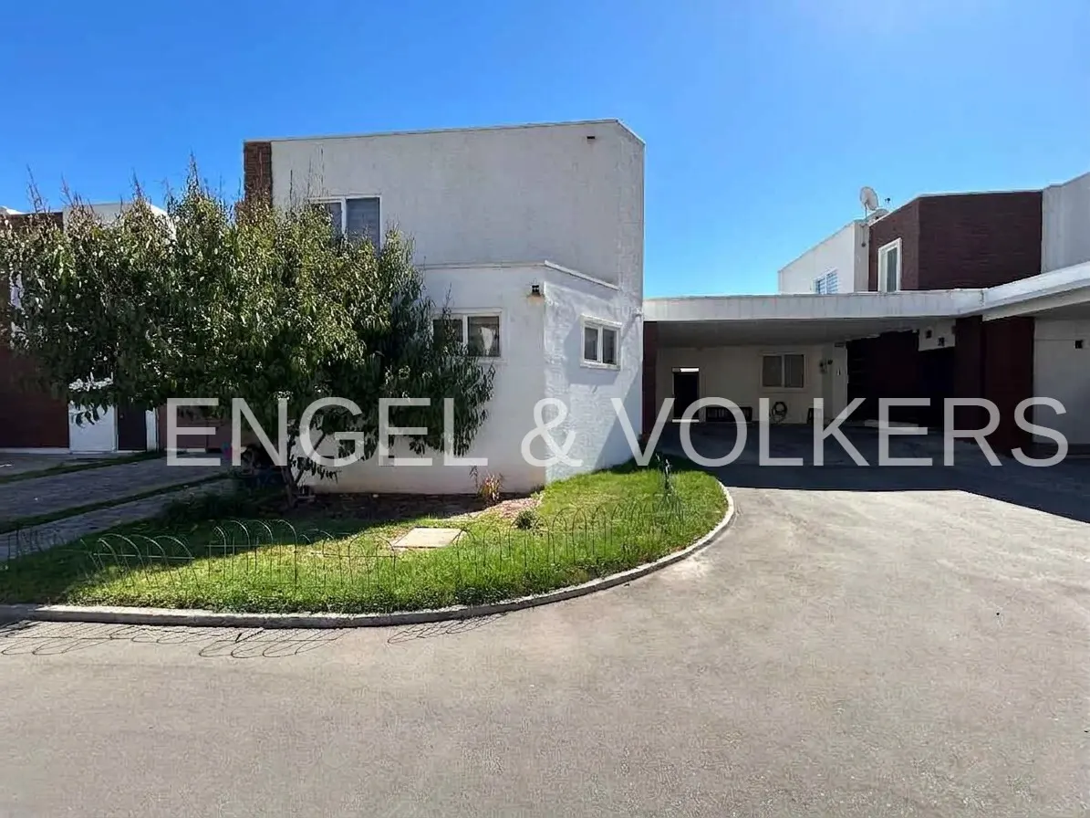 Exterior of a two-story white house with a carport and a green lawn in front. The sky is blue.