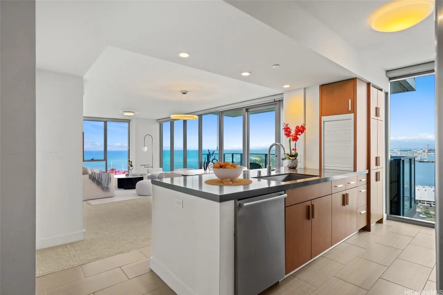 A modern kitchen with white cabinets, stainless steel appliances, and a view of the ocean.