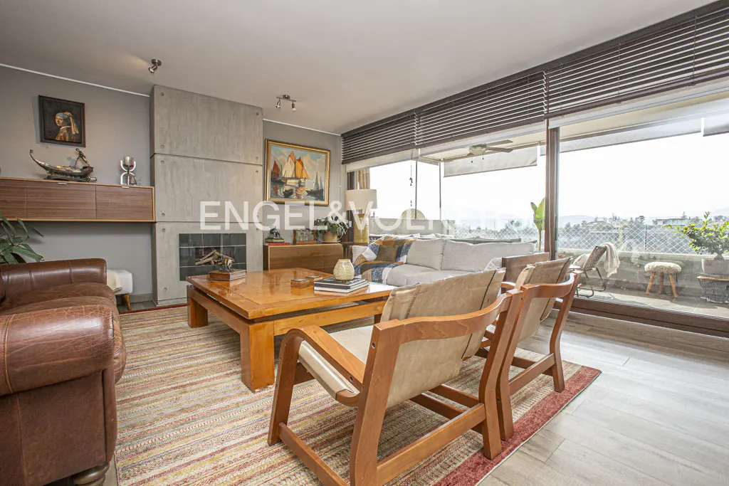 A bright living room with a fireplace, wooden furniture, and a large window with a view.