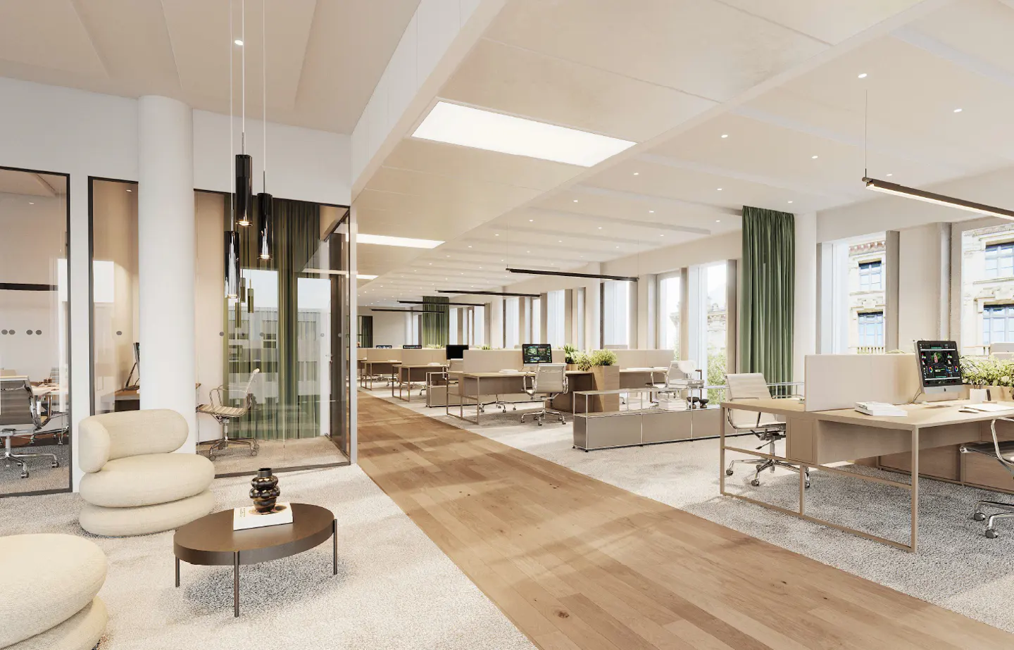 Bright, modern office space with desks, chairs, and computers. A lounge area features a round table and cream-colored chairs. Large windows provide natural light.
