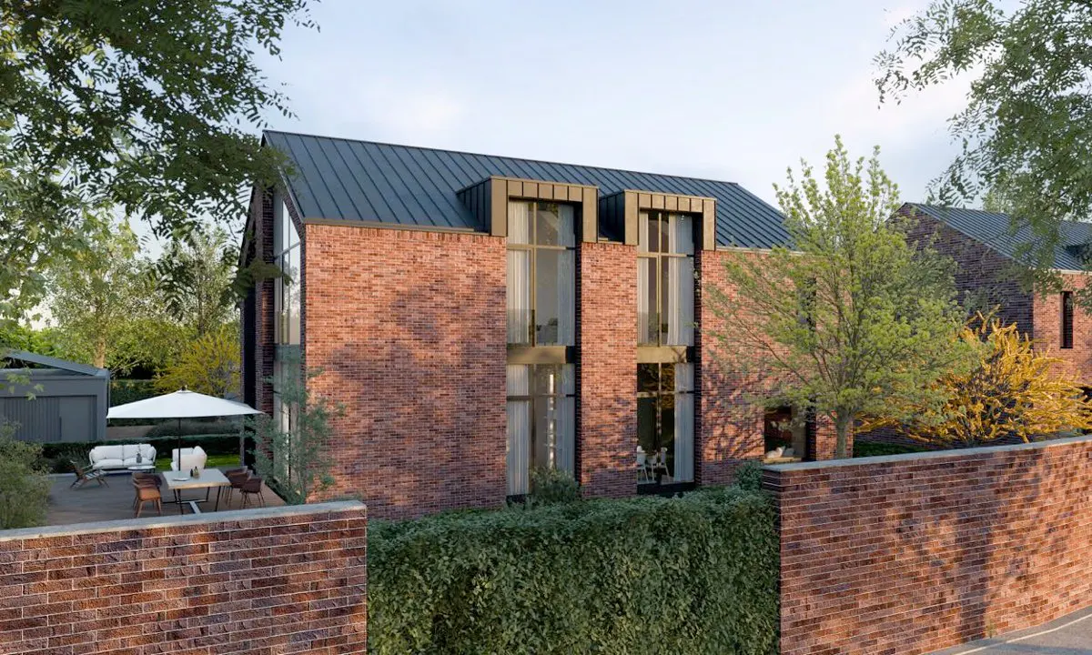 Modern red brick house with a dark metal roof, tall windows, and a patio with outdoor furniture behind a brick wall.
