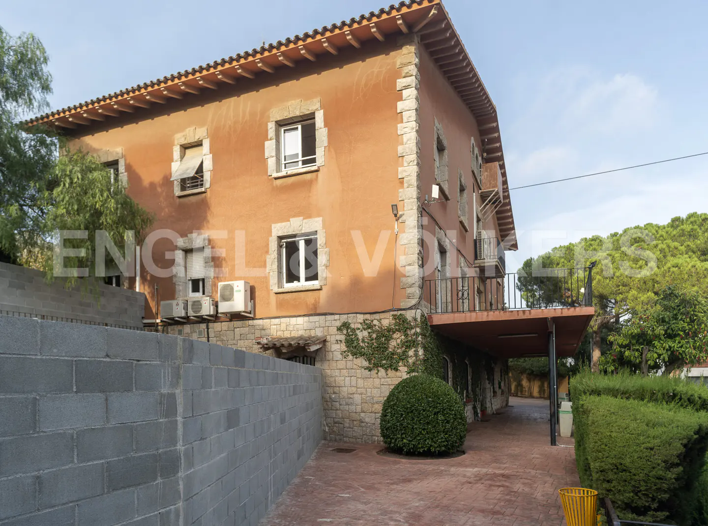 Exterior view of a two-story orange building with stone accents, a brick walkway, and green landscaping.