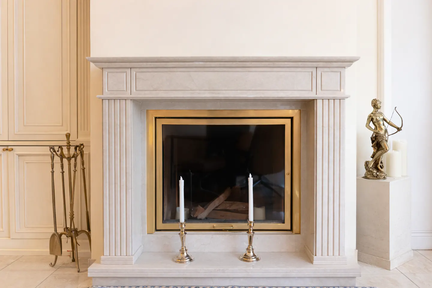 Elegant living room with a marble fireplace, gold accents, and a statue of a woman with a bow and arrow.