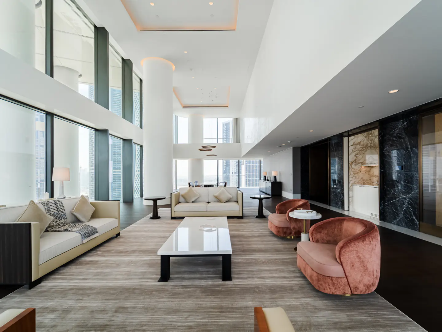 A modern living room with sofas, chairs, a white table, and large windows with a city view.