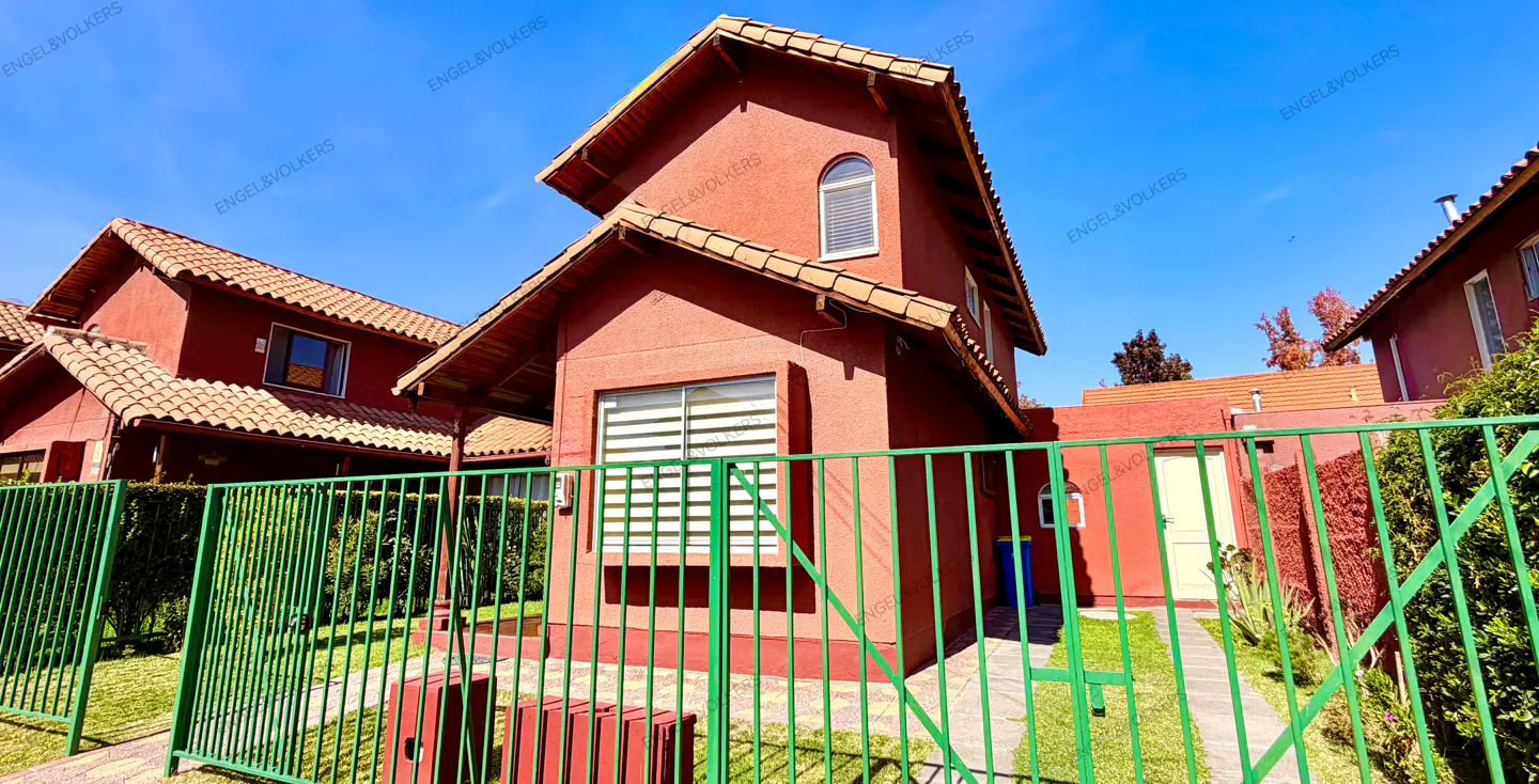 Exterior view of a red two-story house with a green fence, lawn, and blue sky.