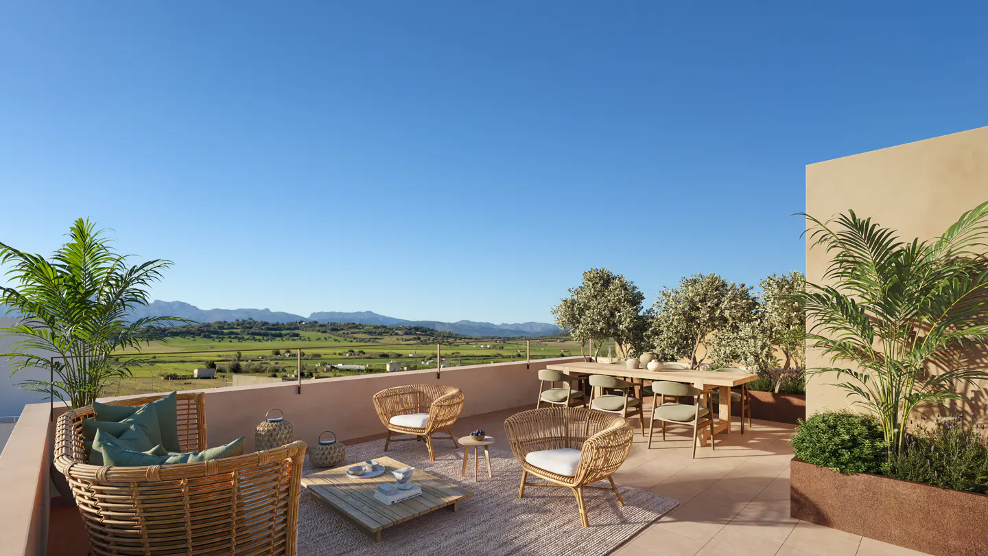 Rooftop patio with wicker furniture, a wooden table, and potted plants. A scenic view of green fields and mountains is visible in the background.