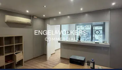 Interior view of an Engel & Völkers commercial office with gray walls, a reception desk, and a light wood shelf.