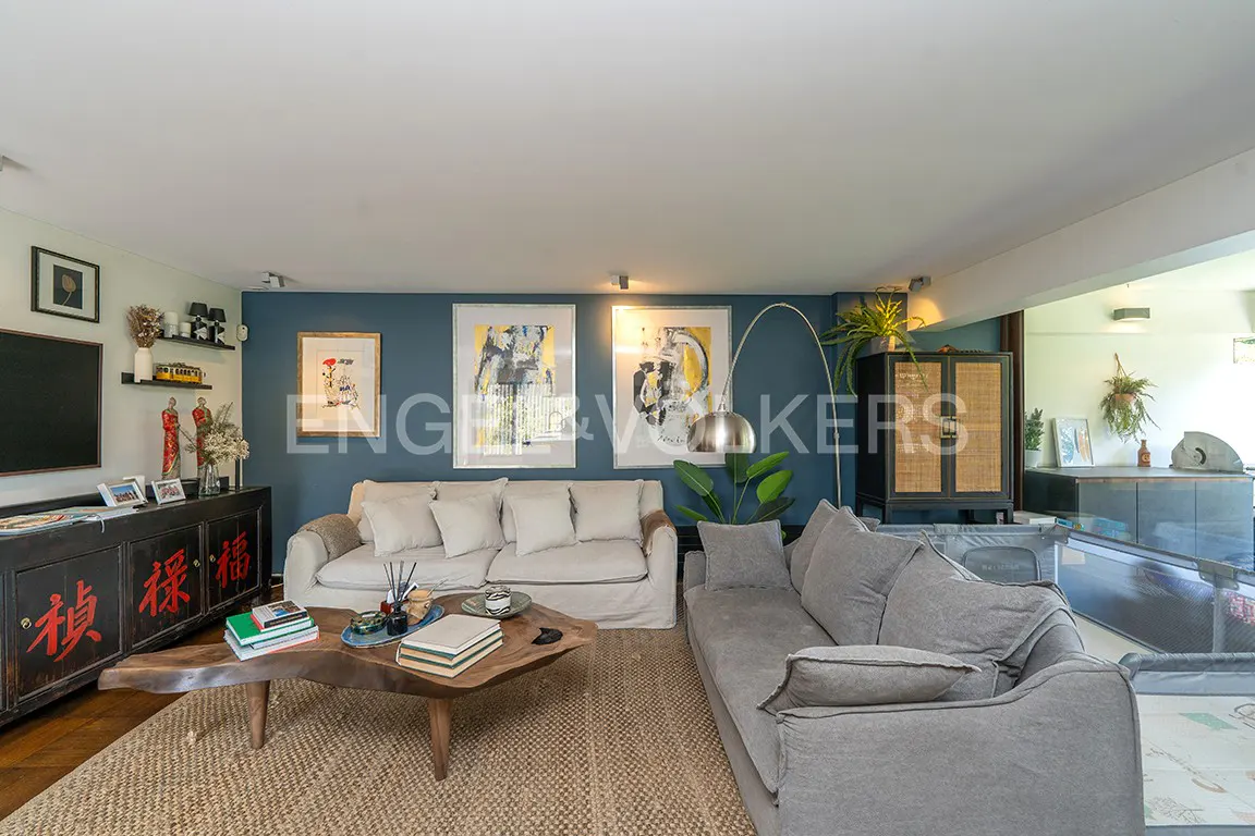 Living room with a gray sofa, a white sofa, a wooden table, and a blue wall with paintings.