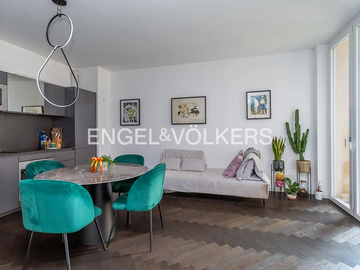 Open-concept living space with teal chairs around a marble table, a daybed, and herringbone wood floors.