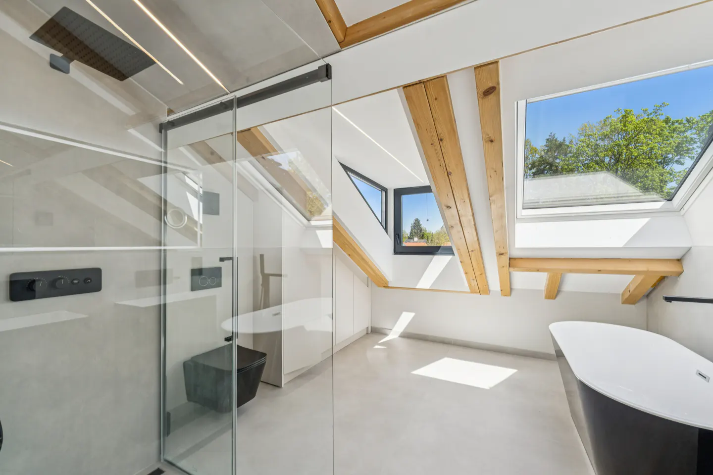Modern bathroom with a glass shower, black toilet, and a black and white tub. Exposed wooden beams and skylights add natural light.