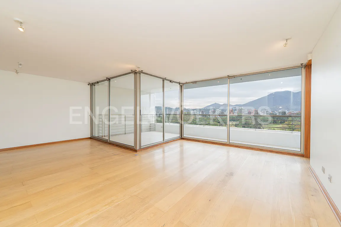 Bright, empty room with light wood floors, white walls, and floor-to-ceiling windows offering a city view.