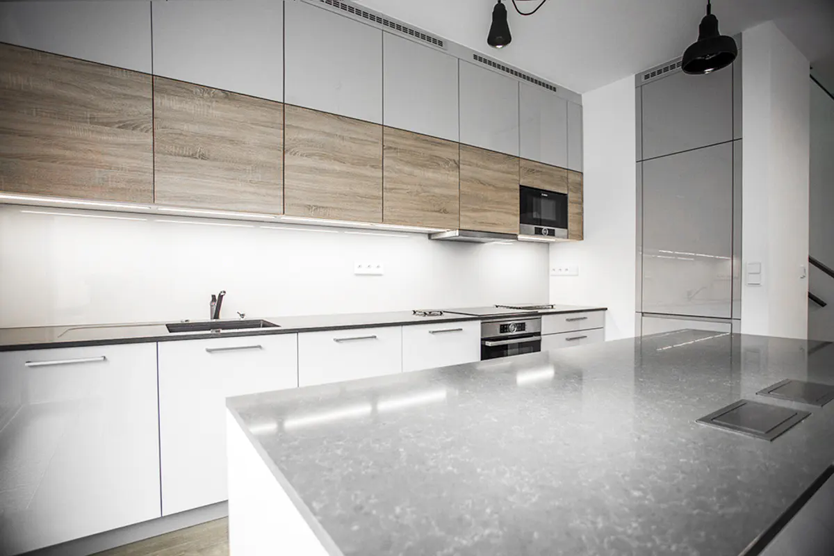 Modern kitchen with white and wood-grain cabinets, a large stone island, and integrated stainless steel appliances.