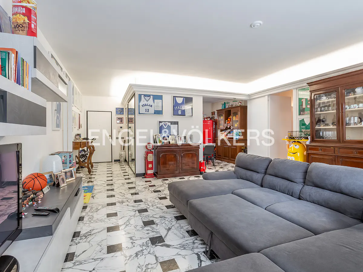 Living room with gray sectional sofa, marble floors, and sports memorabilia. A red gas pump and vintage cabinets add character.
