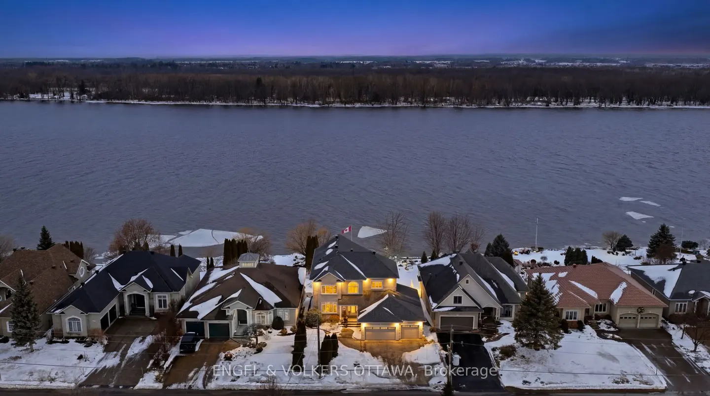 Aerial view of waterfront homes at dusk, snow on the ground, and a Canadian flag on one roof.