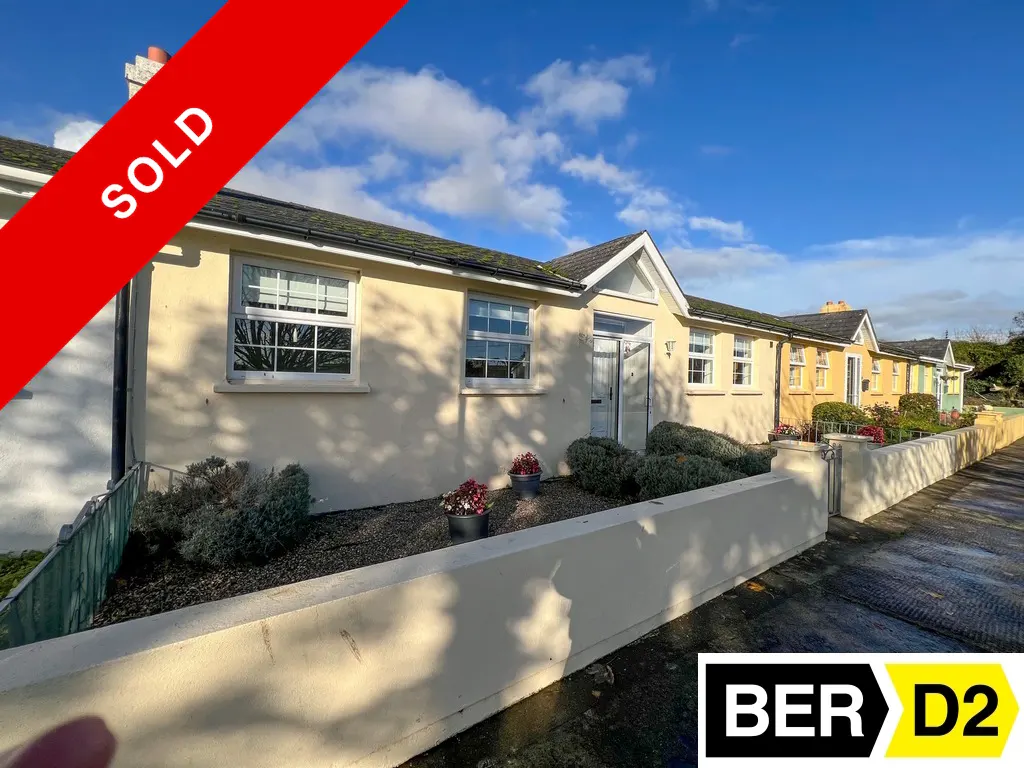 A row of single-story, light yellow houses with white trim, under a blue sky. A red "SOLD" banner is in the upper left. BER D2 logo in the lower right.