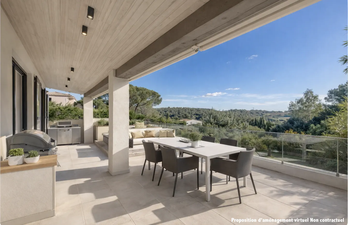 Covered patio with outdoor kitchen, dining table, and seating area overlooking a green landscape under a blue sky.