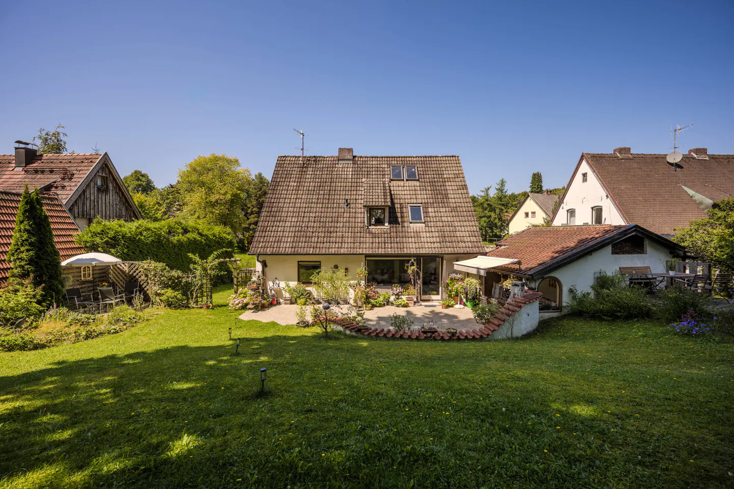 A house with a brown tile roof and a green lawn on a sunny day.